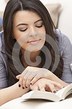 Hispanic Woman Reading Paperback Book at Home