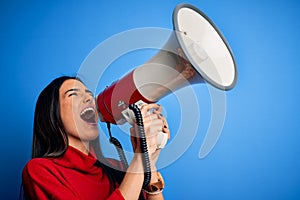 Hispanic woman shouting angry on protest through megaphone