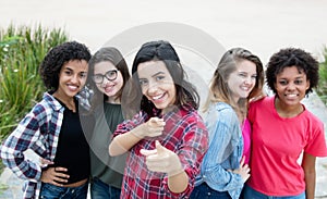 Hispanic woman showing thumb with group of girlfriends