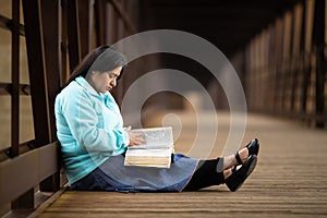 Hispanic Woman Sitting On A Bridge And Reading Bible