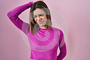 Hispanic woman standing over pink background confuse and wondering about question