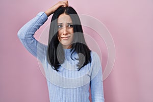Hispanic woman standing over pink background confuse and wondering about question