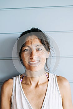 Portrait of hispanic woman with summer dress and ponytail while leaning on wood wall