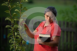Hispanic Woman Touching Pear Tree and Contemplating her Bible