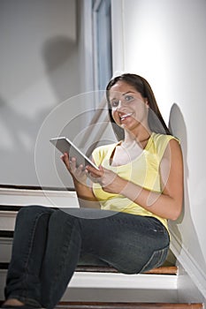 Hispanic woman using tablet computer on stairs