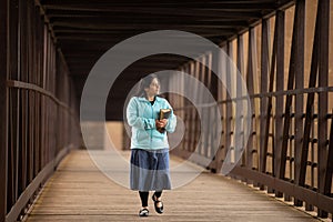 Hispanic Woman Walking Down A Bridge With Her Bible