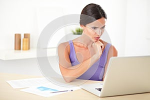 Hispanic woman wondering while working on laptop