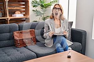 Hispanic woman working at consultation office angry and mad screaming frustrated and furious, shouting with anger