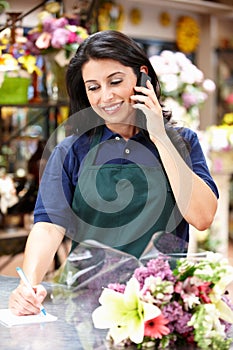 Hispanic woman working in florist on phone