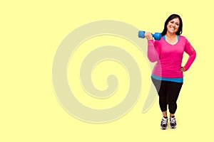 Hispanic Woman In Workout Clothes Holding Dumbbell Against A Bright Yellow Background