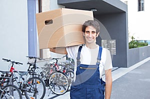 Hispanic worker with box in front of a building