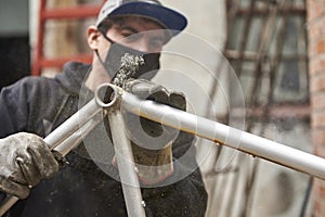 Hispanic worker removing the paint of a bicycle frame at his workshop