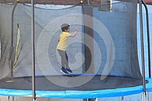 Hispanic 6-year-old boy jumping on a brincolin as a physical activity for a healthy life he exercises and has fun alone at home photo