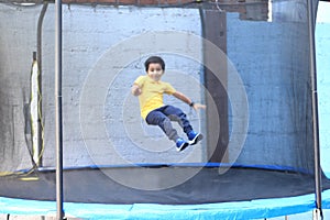 Hispanic 6-year-old boy jumping on a brincolin as a physical activity for a healthy life he exercises and has fun alone at home photo