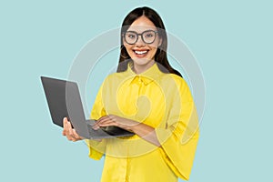 Hispanic young happy woman professional manager typing on laptop at blue background