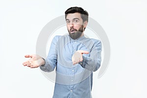 Hispanic young man with a beard is indignant and throwing up hands.