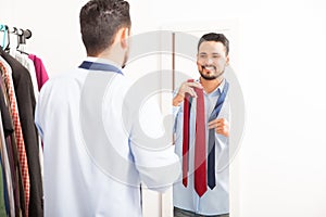 Hispanic young man choosing a tie at home