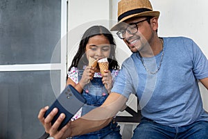 hispanic young man dad with a chil girl kid taking selfies while eating gelato ice cram at the park photo
