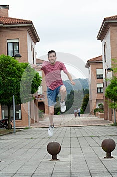 Hispanic young man jumping on metal ball in the street in Cudillero, Spain, vertical shot