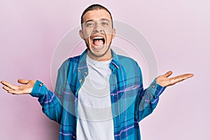 Hispanic young man wearing casual clothes celebrating victory with happy smile and winner expression with raised hands