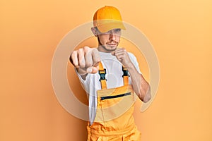 Hispanic young man wearing handyman uniform punching fist to fight, aggressive and angry attack, threat and violence