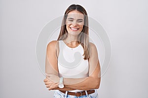 Hispanic young woman standing over white background happy face smiling with crossed arms looking at the camera