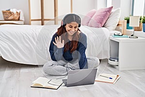 Hispanic young woman using laptop sitting on the floor at the bedroom looking positive and happy standing and smiling with a