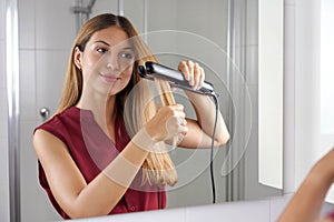 Ispanico giovane donna vapore piastra per capelli sul stile capelli Specchio sul il bagno 