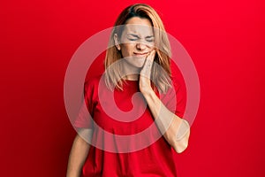 Hispanic young woman wearing casual red t shirt touching mouth with hand with painful expression because of toothache or dental