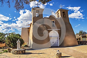 Historic adobe San Francisco de Asis Mission Church in Taos New Mexico in dramatic late afternoon light under intense blue sky wit photo