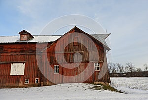 Historic antique red barn after winter snowfall