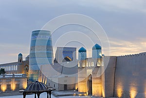 Historic architecture of Kalta Minor minaret old at square and Castle gate with illumination at sunset in Itchan Kala inner town