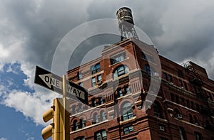 Historic brick building in New York City with water tower on top, stoplight in foreground