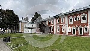 Historic brick building in serene park setting with a cloudy sky background
