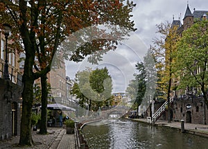 Historic canal in the city center of Utrecht in the netherlands during fall with leaves covering the ground