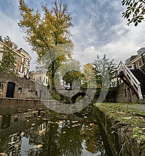 Historic canal in the city center of Utrecht in the netherlands during fall with leaves covering the ground