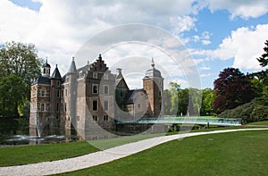 Historic castle with modern glass bridge in park with trees and grass field. Ruurlo, Gelderland, the Netherlands.