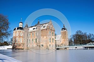 Historic castle in winter landscape with snow and frozen moat. Sunny day with bright blue sky, low angle perspective. Old medieval
