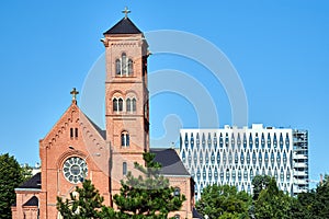 A historic Catholic church with a bell tower and a facade of a modern office building