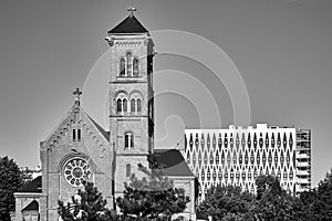 A historic Catholic church with a bell tower and a facade of a modern office building