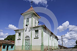 Historic church in white and green with red steeple roof against blue sky and white clouds, Diamantina, Minas Gerais, Brazil