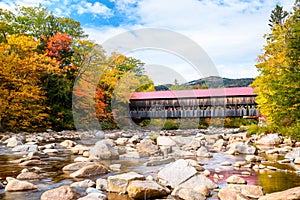 Historic covered bridge in New England in a partly cloudy autumn day