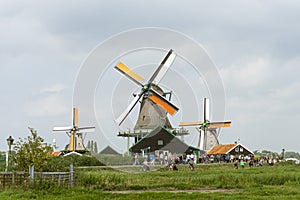 Historic Dutch Windmills at the village of Zaanse Schans in the Netherlands. Beautiful landscape with green grass a cloudy day
