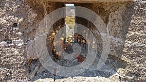 An historic Embrasure, loophole in an old wall of an fortress. Rhodes. Greece. View from the inside. Dry flower in a loophole in a