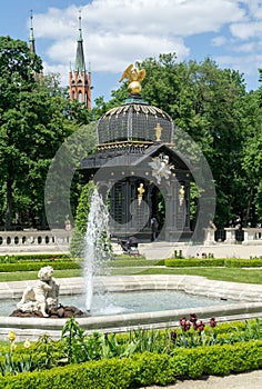 A historic gazebo decorated with sculptures, gold Griffin sculpture on the roof in the gardens of the Branicki Palace,