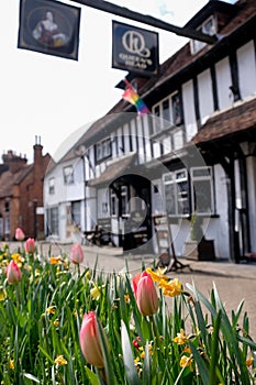 Historic half timbered Tudor pub called the Queen`s Head, in Pinner High Street, Pinner, Middlesex UK. Tulips in foreground.