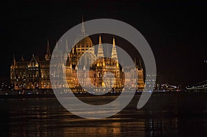 Historic Hungarian parliament building in Budapest at night. The river Danube and reflection of the building in