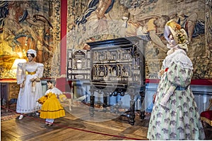 Historic installation with antique furniture and dolls dressed in vintage costumes, France.