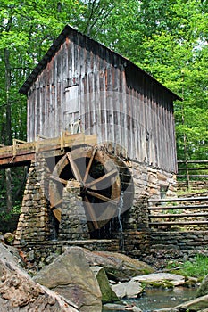 A historic mill in a forest with green leafs in late spring.