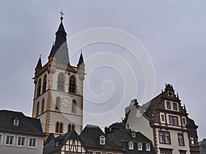 Historic old buildings at square Hauptmarkt in city Trier, Germany with steeple of Catholic church St. Gangolf on cloudy day.